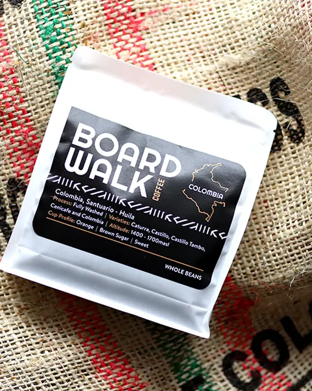 A white Boardwalk Colombia coffee bag on a Colombian burlap sack.
