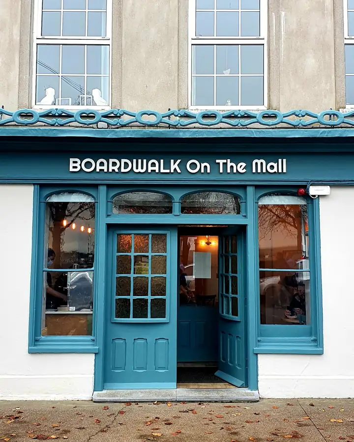 The teal shopfront of Boardwalk on the Mall, glazed double doors and the sign above.